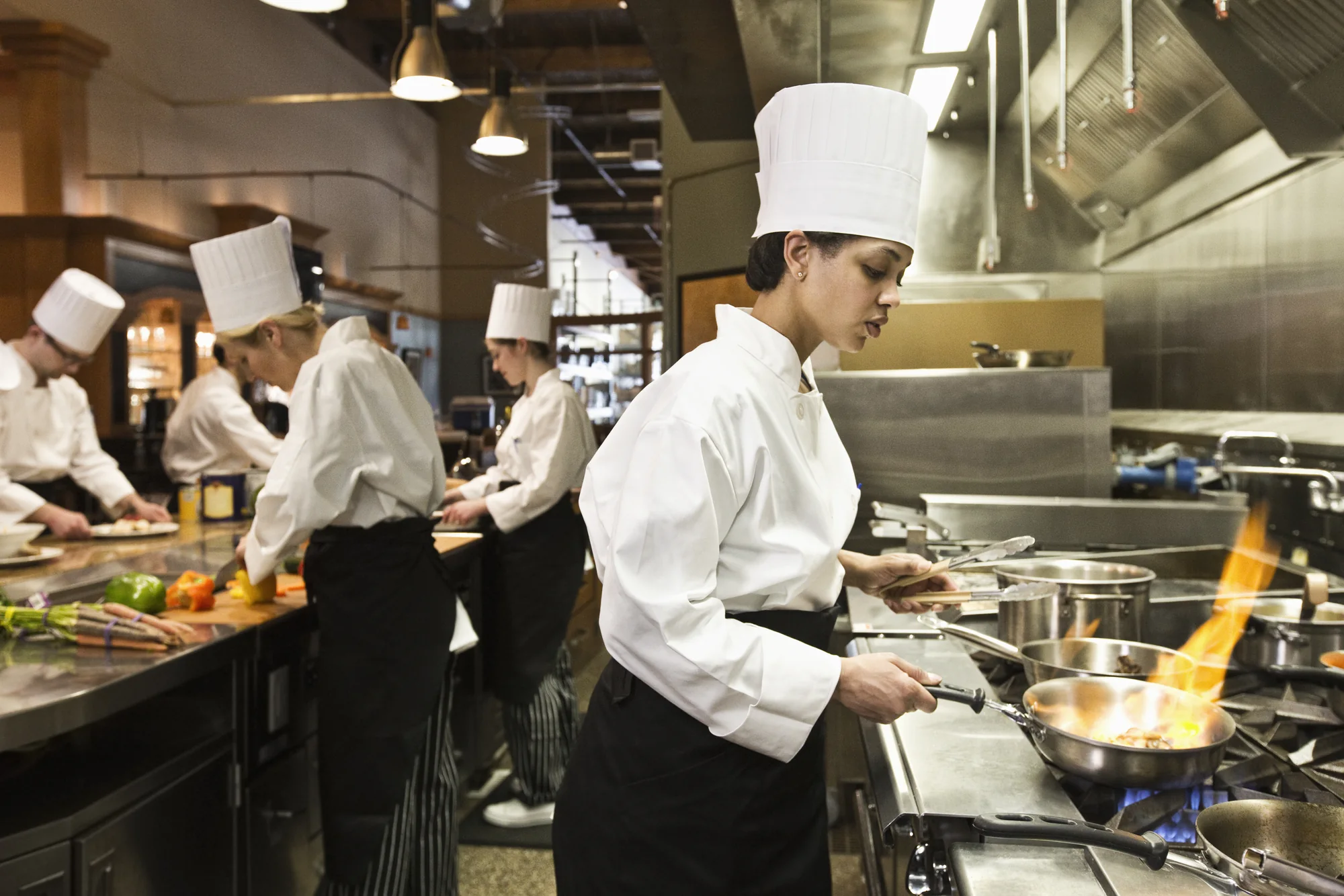 Chefs working with commercial equipment in a busy restaurant kitchen