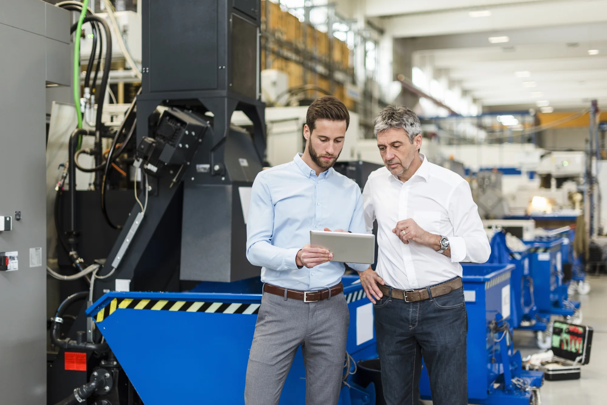 Business professionals reviewing industrial equipment and financing information on a tablet