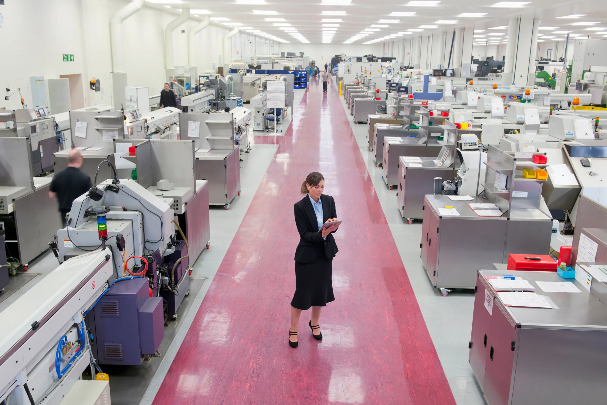 Manufacturing professional using a tablet beside modern factory equipment