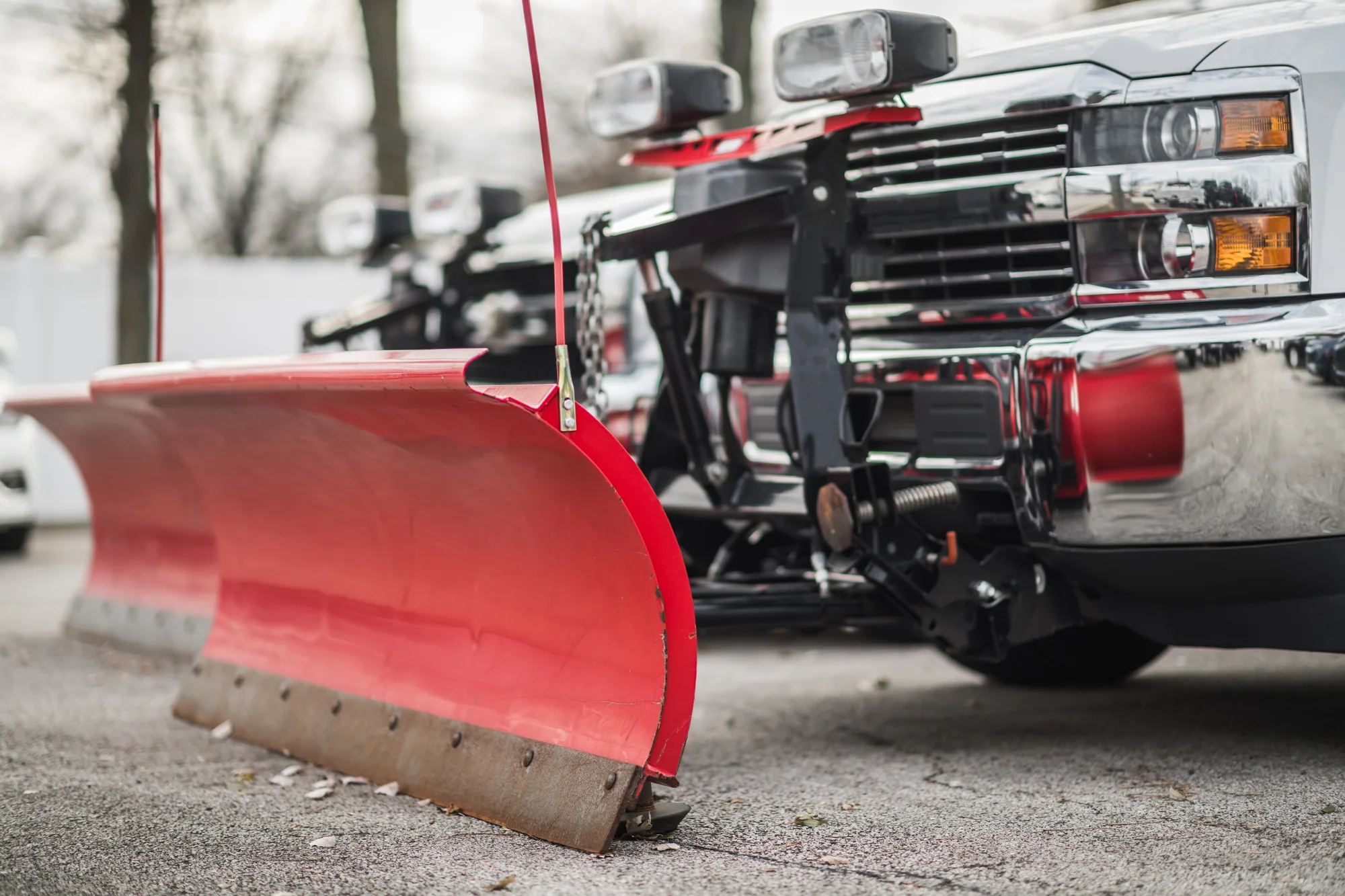 Commercial pickup trucks fitted with red snow plow blades for winter operations