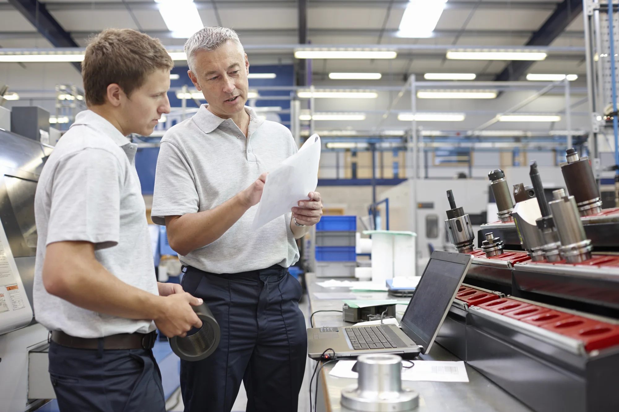 Equipment vendor and customer discussing machinery in an engineering warehouse